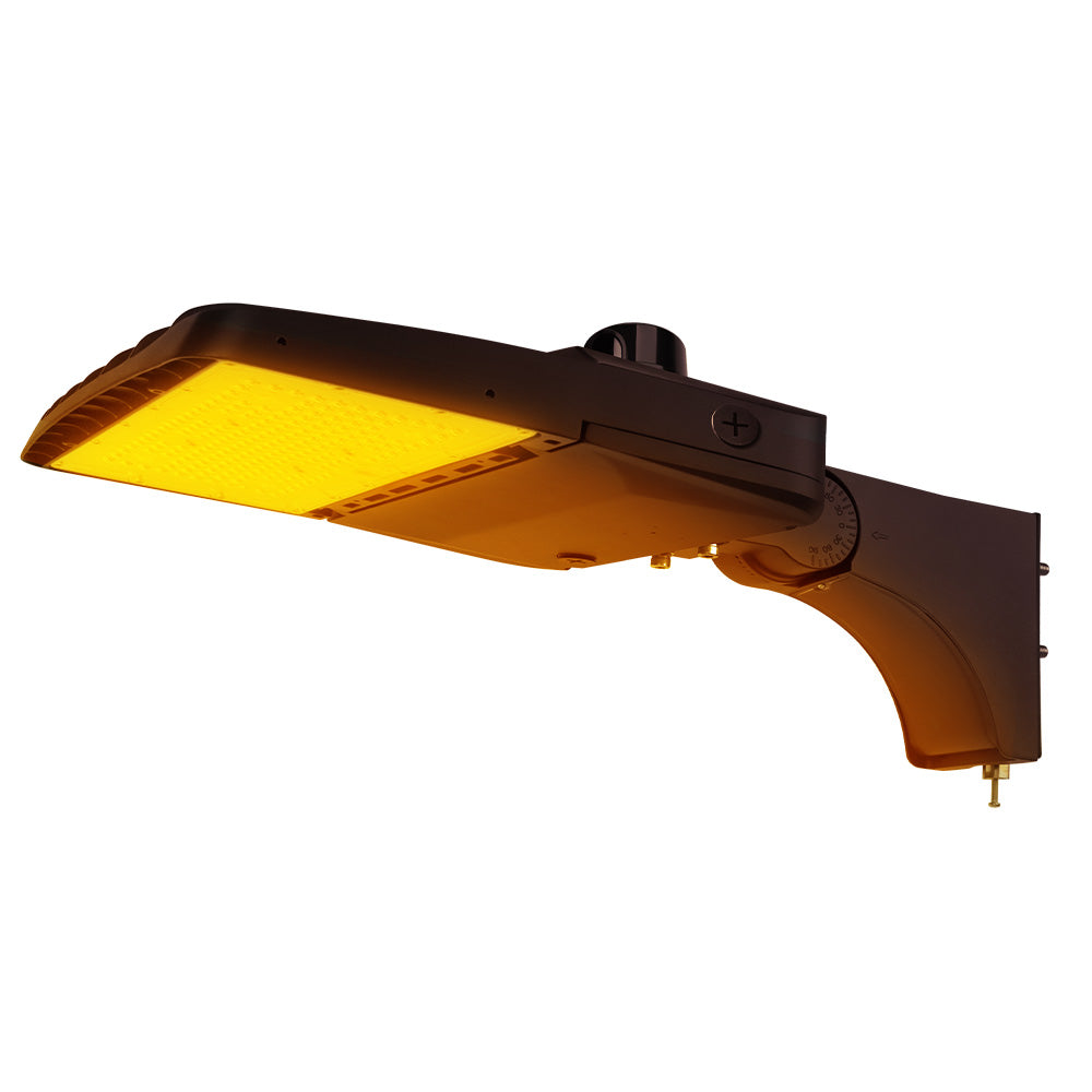 Vela Amber LED Area Light in Dark Bronze with extrusion arm and Photocell.